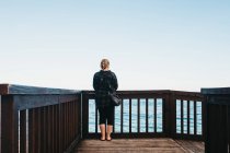 Rückenansicht einer jungen Frau in lässigem Outfit, die am Geländer einer Böschung steht und einen bewundernden Blick auf das wunderschöne Meer in Altea, Spanien — Stockfoto