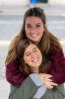 Lady hugging from back cheerful young attractive woman — Stock Photo