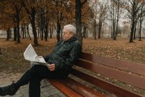 Літній чоловік читає газету в парку — стокове фото