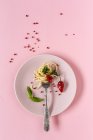 Спагетті з томатом і соусом песто на тарілці на рожевому фоні — стокове фото