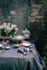 Tablecloth setting with artichokes, flowers and red wine — Stock Photo
