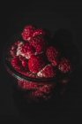 Крупный план вкусной спелой малины, лежащей в стеклянной банке в темной комнате — стоковое фото