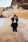 Jeune femme pieds nus utilisant un appareil photo alors qu'elle se tenait sur le bord de la mer à Altea, Espagne — Photo de stock