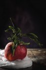 Raw red apple with leaves on dark wooden table — Stock Photo