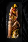 Paella casera con cangrejos de río y gambas servidas en pizarra sobre tela negra - foto de stock