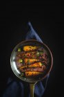Gesunde geröstete Karotten mit Kräutern und Gewürzen in der Pfanne auf schwarzem Hintergrund — Stockfoto