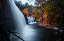 Splashing waterfall and autumn forest foliage — Stock Photo