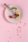 Spaghetti mit Tomaten-Pesto-Sauce auf Teller auf rosa Hintergrund — Stockfoto