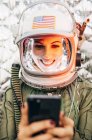 Astronauta femenina en casco vintage iluminado con teléfono móvil - foto de stock
