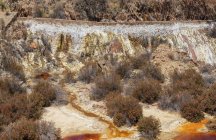 Small streams of dirty water flowing on slope of pit in Santo Domingos Mine in Portugal — Stock Photo