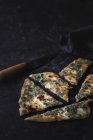 Slices of baked gozleme on dark surface with knife — Stock Photo
