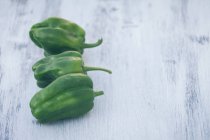 Fresh green peppers on white wooden table — Stock Photo