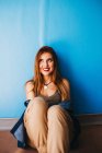 Attractive woman sitting near blue wall — Stock Photo