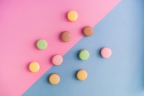 From above collection of bright delicious macarons on pink and blue background — Stock Photo