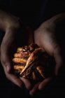 Close-up de mãos humanas segurando pequeno pão de chocolate no fundo escuro — Fotografia de Stock