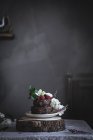 Schokoladenkuchen mit Himbeeren und Blumen auf Teller auf Holzständer serviert — Stockfoto