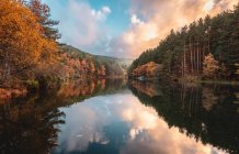 Calmo rio entre floresta de outono e colinas ao nascer do sol — Fotografia de Stock