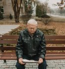 Elderly man reading newspaper in park — Stock Photo