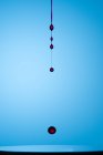 Крупный план брызг прозрачной жидкости цвета на синем фоне — стоковое фото