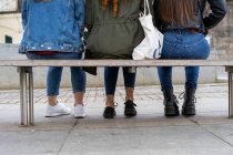 Giovani donne in abbigliamento casual sedute sulla panchina — Foto stock