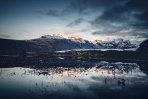 Landscape of remote cold mountains reflecting in tranquil water with snow lying on ground, Iceland — Stock Photo