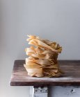 Pile of wheat pappardelle spaghetti on old wood table on grey background — Stock Photo