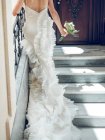 Back view of crop woman in elegant wedding dress holding small bouquet and walking up stairs inside beautiful building — Stock Photo