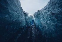 Человек забирается в красивую голубую ледяную пещеру — стоковое фото