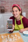 Teenagermädchen benutzt das Smartphone, während sie an traditionellem Gebäck arbeitet — Stockfoto