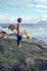 Guy standing with bright surfboard on coast near ocean with surfboard — Stock Photo