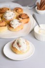 Plates with yummy cinnamon buns with vanilla cream. — Stock Photo