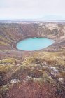 Desde arriba lago en el cráter entre la muerte tierras marrones y colinas con el cielo? en las nubes en Islandia - foto de stock
