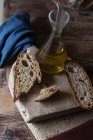 Slices of wholemeal bread on rustic wooden chopping board with bottle of oil — Stock Photo