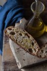 Fette di pane integrale su tagliere rustico in legno con bottiglia di olio — Foto stock