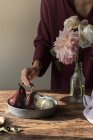 Обрізаний жінкою дегустація з ложкою ванільного морозива і глінтвейном груші в червоному вині на столі з квітами у вазі — стокове фото