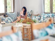 Donna che legge rivista sul divano — Foto stock
