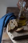 Шматочок цільного хліба на сільській дерев'яній дошці з пляшкою олії — стокове фото