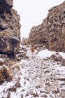 Junger Mann geht in Schlucht mit Schnee zwischen Steinhügeln in Island — Stockfoto