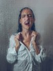 Esguichando mulher na camisa posando na cabine do chuveiro com a língua para fora — Fotografia de Stock