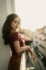 Portrait of passionate young brunette lady standing on balcony in backlit — Stock Photo