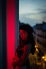 Charming young lady in tank top and beret standing on balcony in redness — Stock Photo