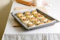 Bunch of small uncooked buns on baking pan on kitchen table. — Stock Photo