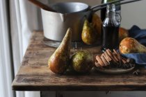 Fresh pears and various aromatic spices on lumber tabletop near bottle of wine and metal saucepan — Fotografia de Stock