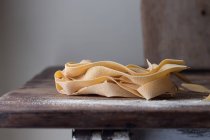 Heap of wheat pappardelle spaghetti on old wood table on grey background — Stock Photo