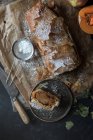 Calabaza casera y strudel de manzana en pergamino con ingredientes sobre fondo oscuro - foto de stock