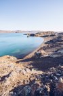 Stone shore of wide river with blue water between hills in Iceland — Stock Photo