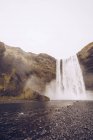 Cascada de agua que cae en el río entre rocas en Islandia - foto de stock