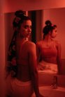 Jovem encantadora de pé no banheiro com reflexo no espelho na vermelhidão — Fotografia de Stock
