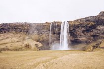 Cascata de água caindo no rio entre rochas na Islândia — Fotografia de Stock