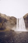 Каскад воды, падающий в реку между скалами Исландии — стоковое фото